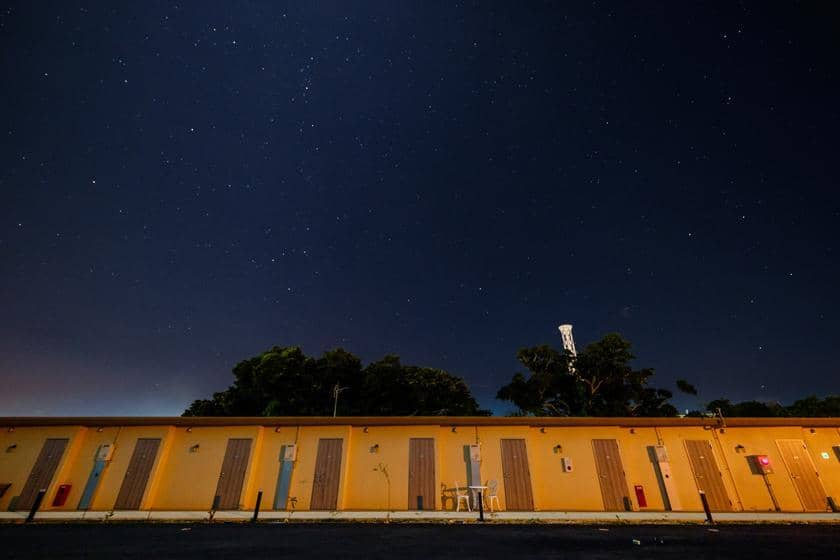 夜空に輝く星々を背景に、黄色い建物のシルエットが浮かび上がる