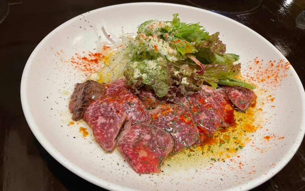 ローストビーフのサラダ仕立て、葉野菜とパルメザンチーズが添えられている