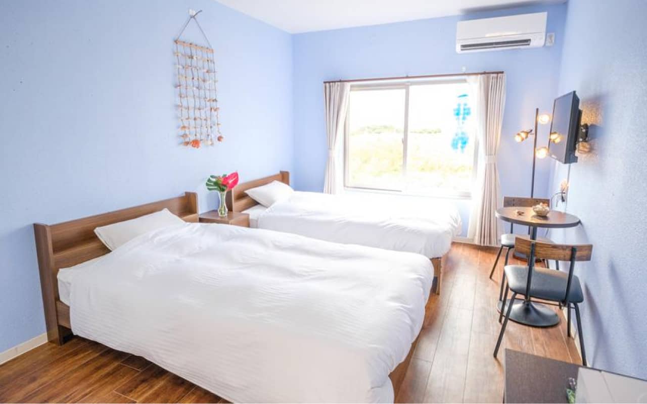 小さなラウンドテーブルと椅子が配置された、落ち着いた雰囲気のツインルーム