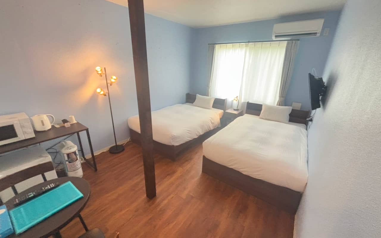 木製床にベッド2台が並ぶ、明るく清潔感のあるツインルームの室内