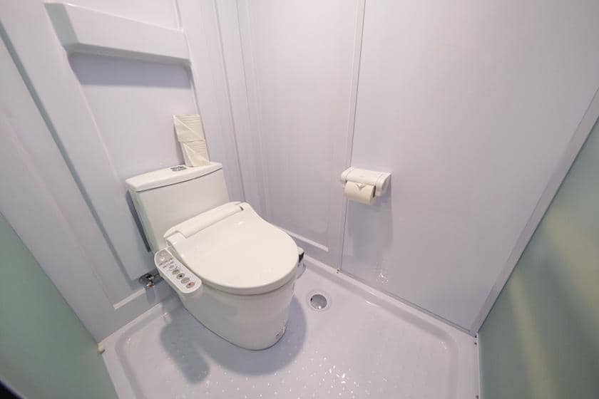 ペーパーホルダーと洋式トイレが設置された宿泊施設のバスルーム