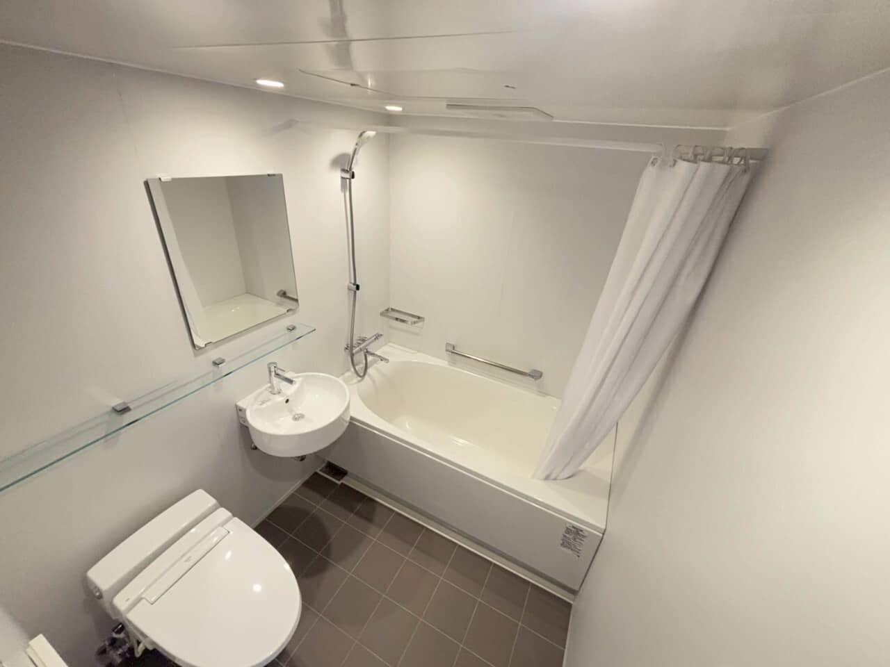 清潔感のある白いユニットバス。浴槽と温水洗浄トイレ付き