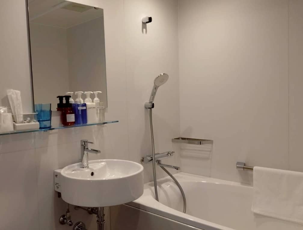 白を基調にした洗面台と浴槽のあるホテルバスルーム