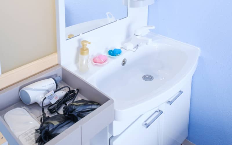 洗面台に置かれたカラフルな石鹸とハンドソープ、整然と整理されたドライヤーなどの備品