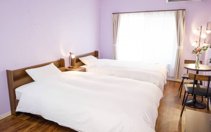ラベンダー色の壁と白いベッドリネンが清潔感と安らぎを与えるツインルーム